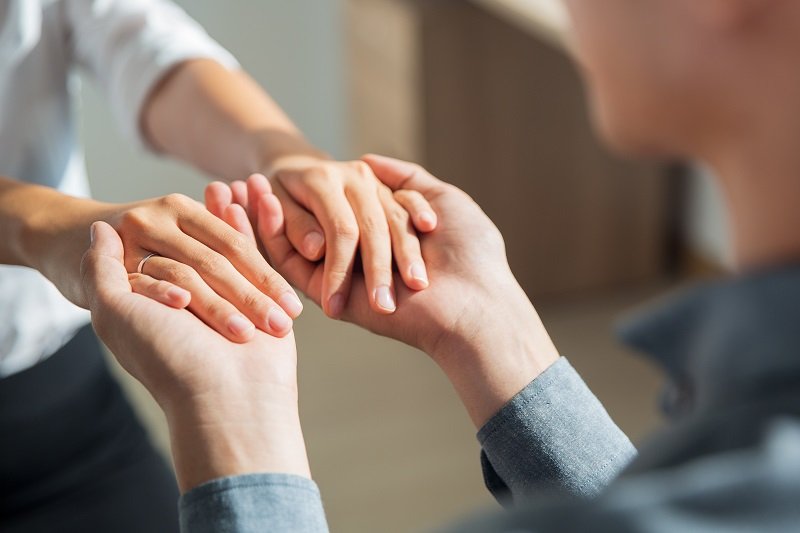 Close-up of hands of young man holding hands of woman. Man proposing to his girlfriend indoors